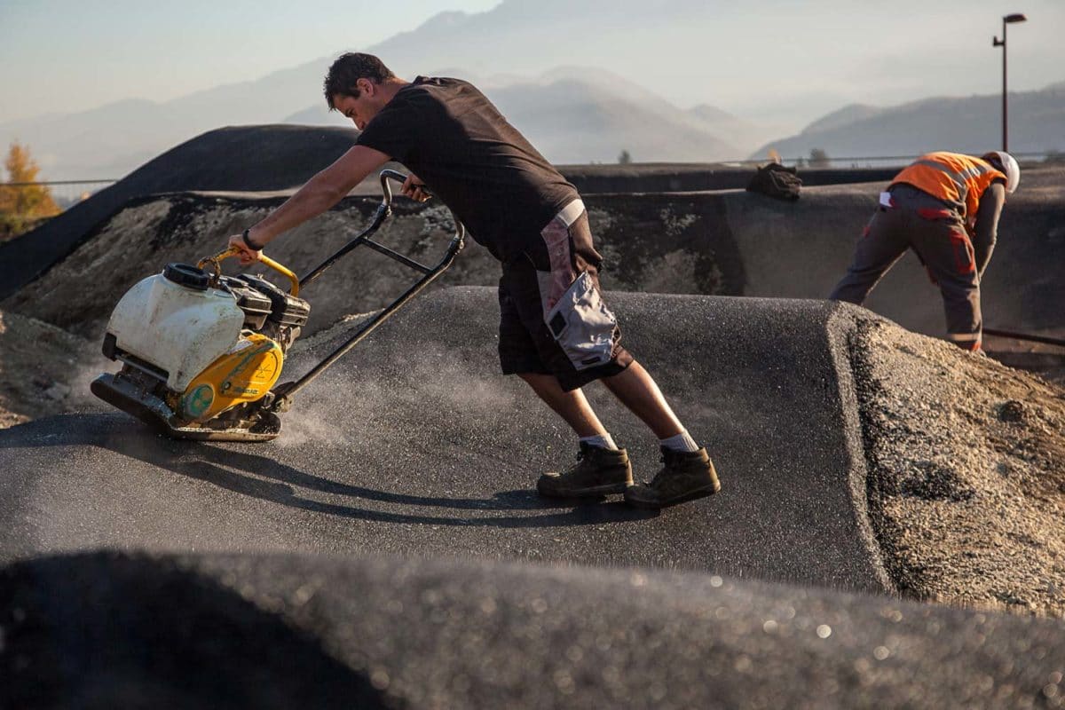 Compactage de l'enrobé sur la bosse d'un pumptrack par un compagnon à la plaque vibrante