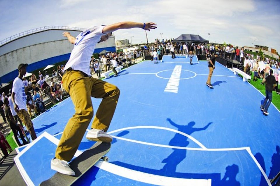 Skateur sur un module installé sur un terrain sportif bleu