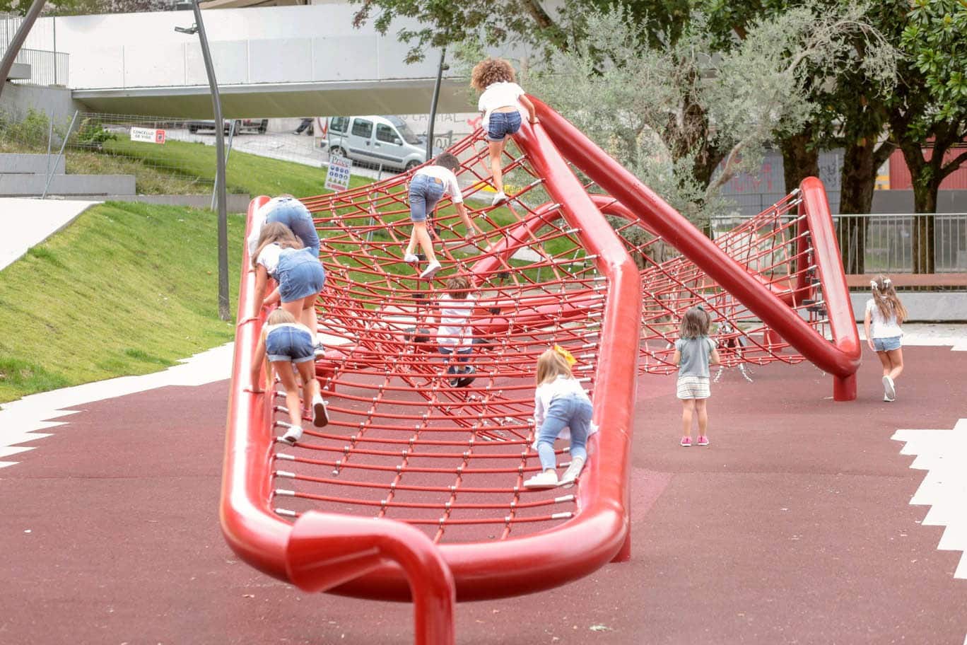 Enfants grimpant sur un filet en corde rouge dans un espace public