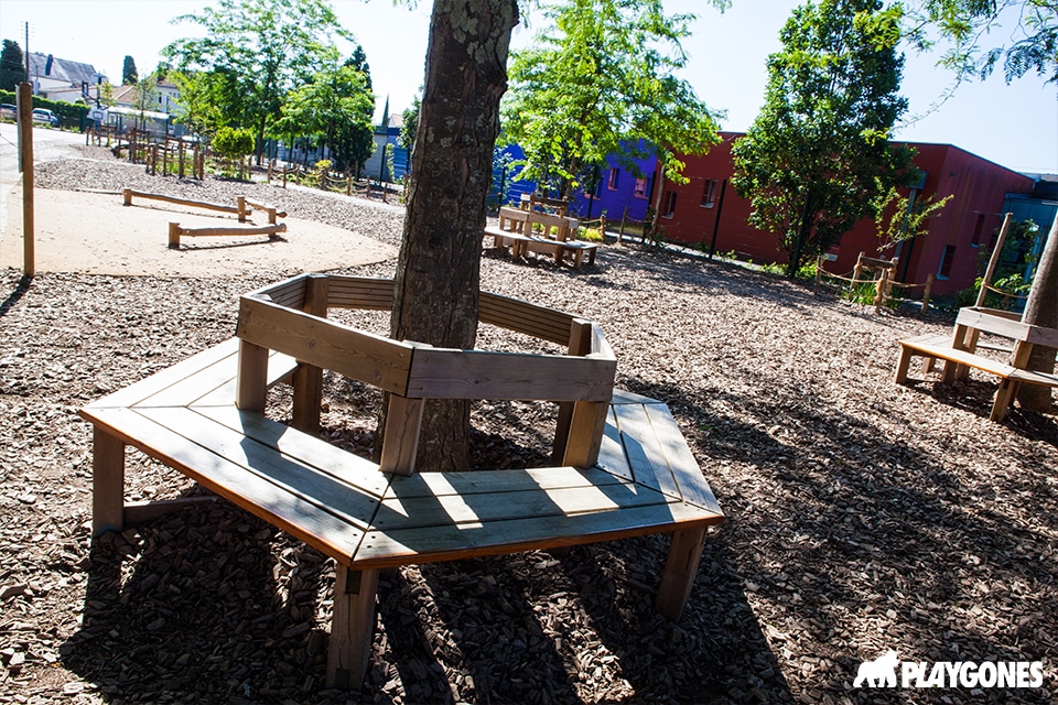 Banc circulaire en bois autour d'un arbre dans une cour d'école végétalisée