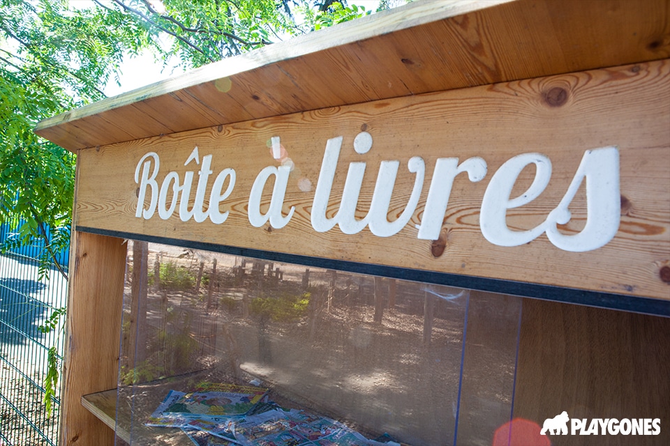 Boîte à livres en bois installée dans une cour oasis