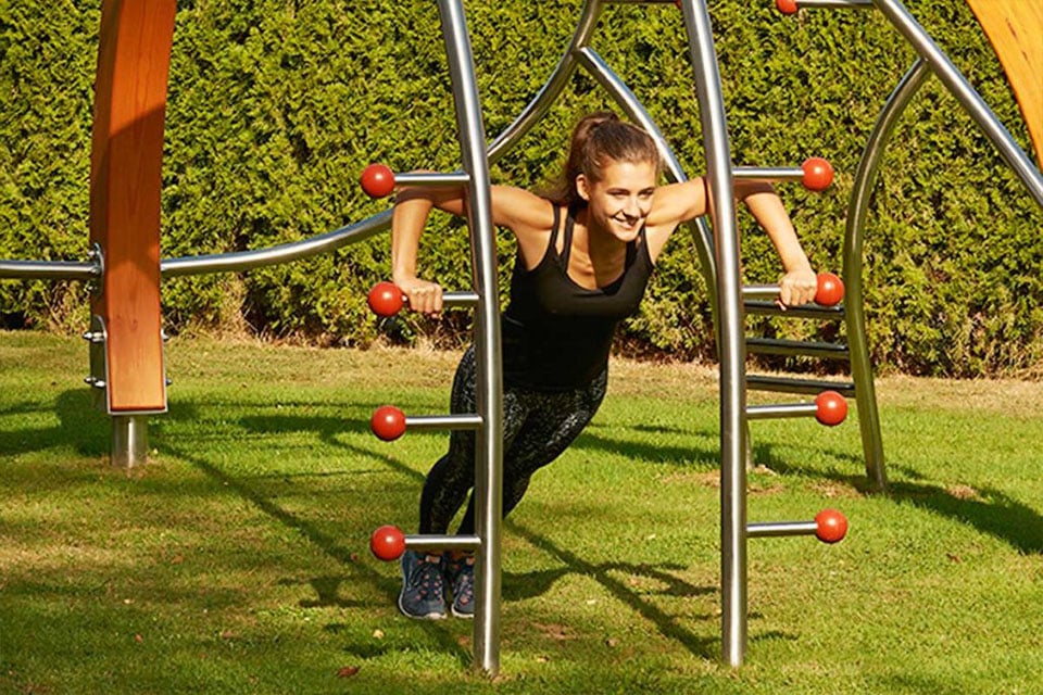 Une fille sur aménagement de gym outdoor dans un parc