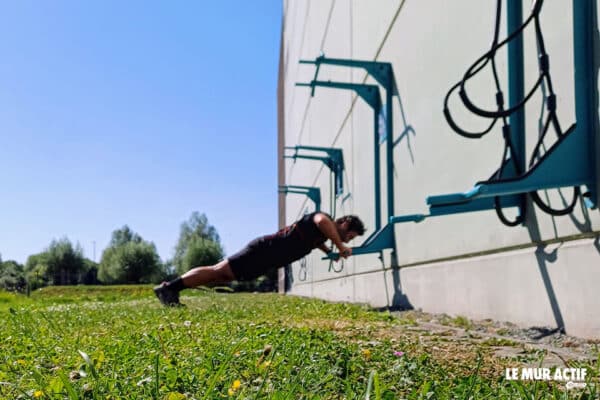 homme faisant des pompes sur un agré de mur actif