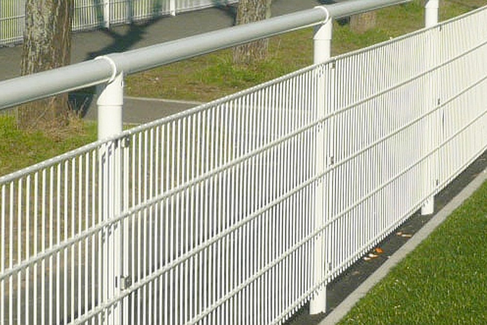 cloture sportive blanche avec une main courante en acier et aluminum autour d'un stade