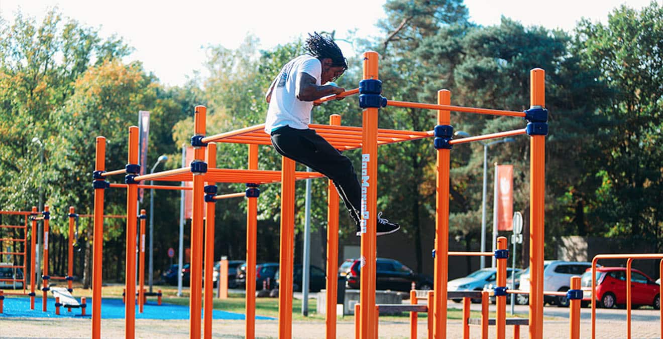 Athlète en mouvement sur une structure de street workout orange