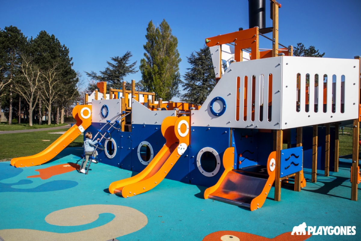 Aire de jeux Téteghem 2023, structure bateau Playgones Grande structure de jeux thème bateau installée à Téteghem par Playgones : toboggans jaunes, parois bleues et orange, sol amortissant EPDM coloré