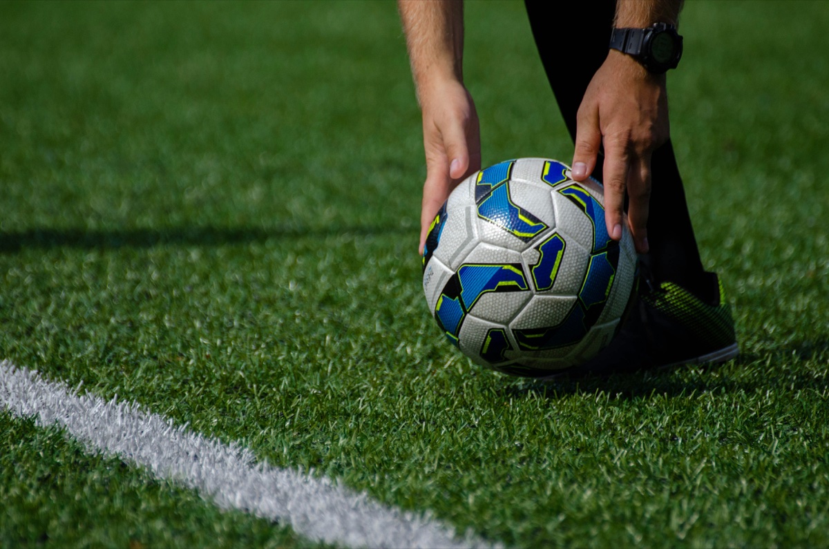 Marquage au sol terrain de football — ligne de touche gazon synthétique Gros plan sur le marquage blanc d'un terrain de football en gazon synthétique : ligne de touche et ballon