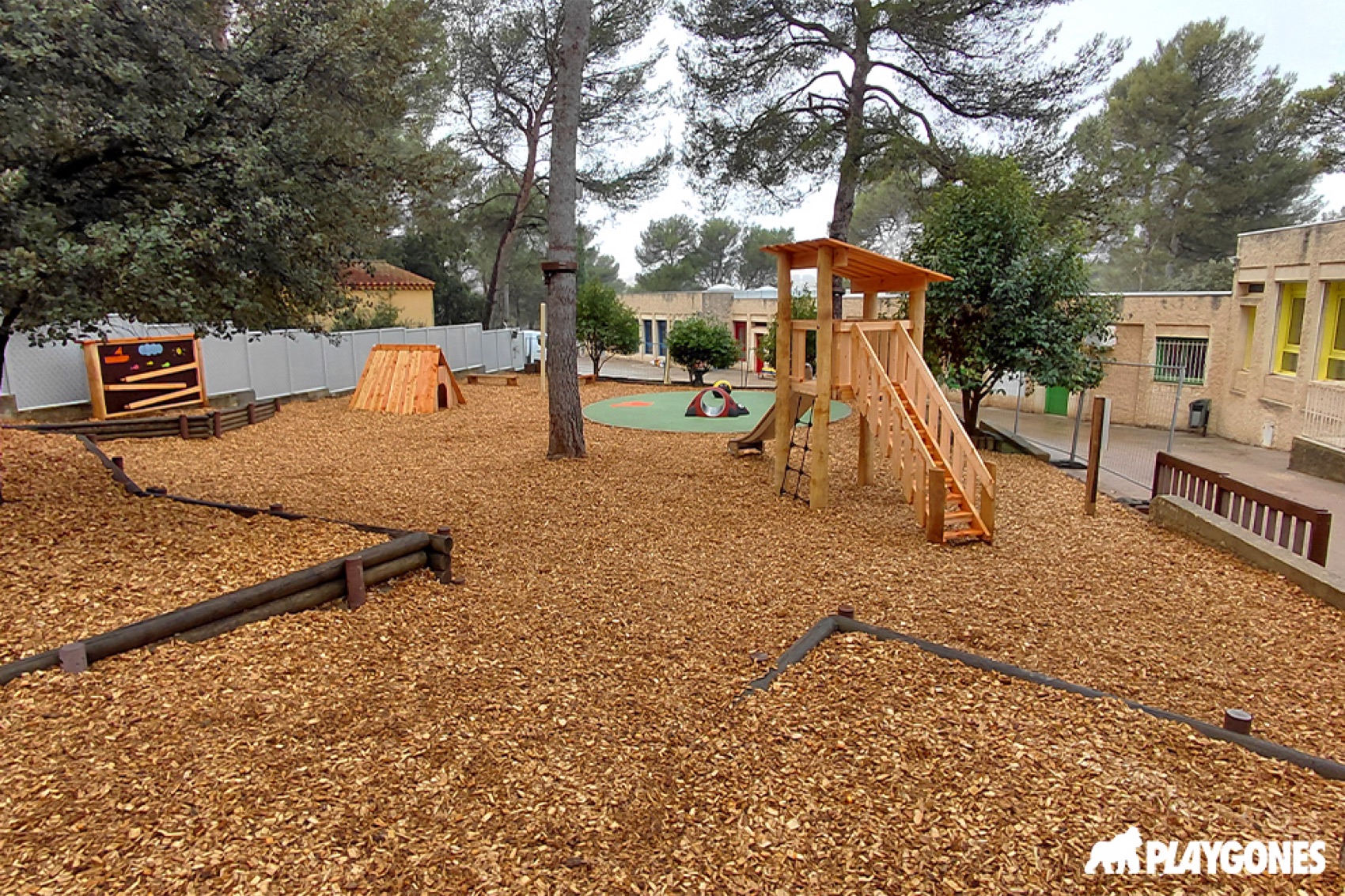 Cour d ecole oasis desimpermeabilisee avec copeaux de bois, arbres et cabanes en bois