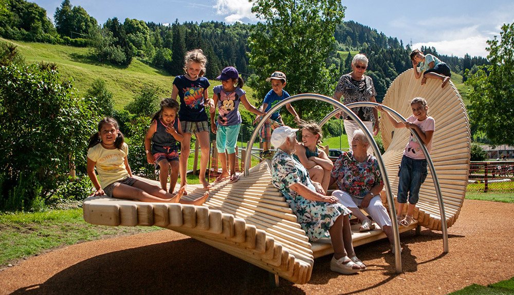 Banc multigénérationnel MoveArt en bois traité Accoya dans un parc, enfants et seniors