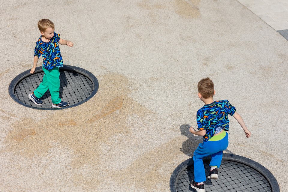 Enfants sautant sur des trampolines enterrés ronds Lapta dans une aire de jeux
