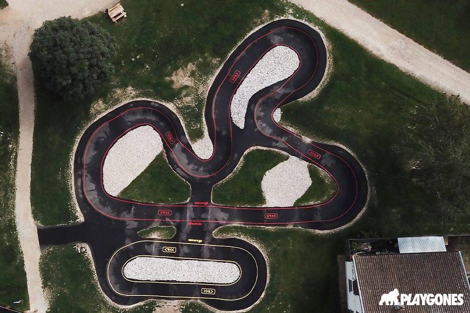 Vue aérienne du pumptrack en enrobé de Saint-André-de-Corcy (Ain), parcours en trèfle avec îlots de galets et pelouse