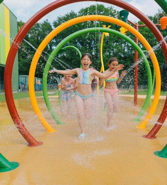Enfants courant sous des arches de jeux d'eau