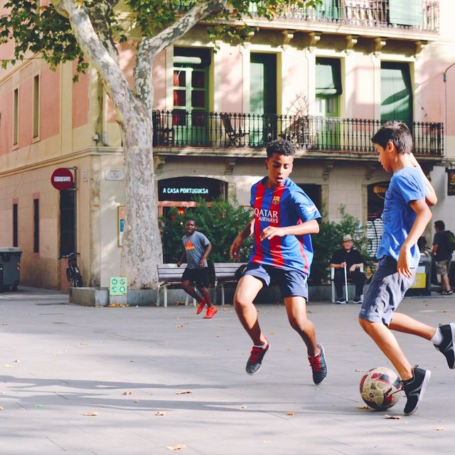 Deux garçons jouent au foot sur une place, en pleine rue